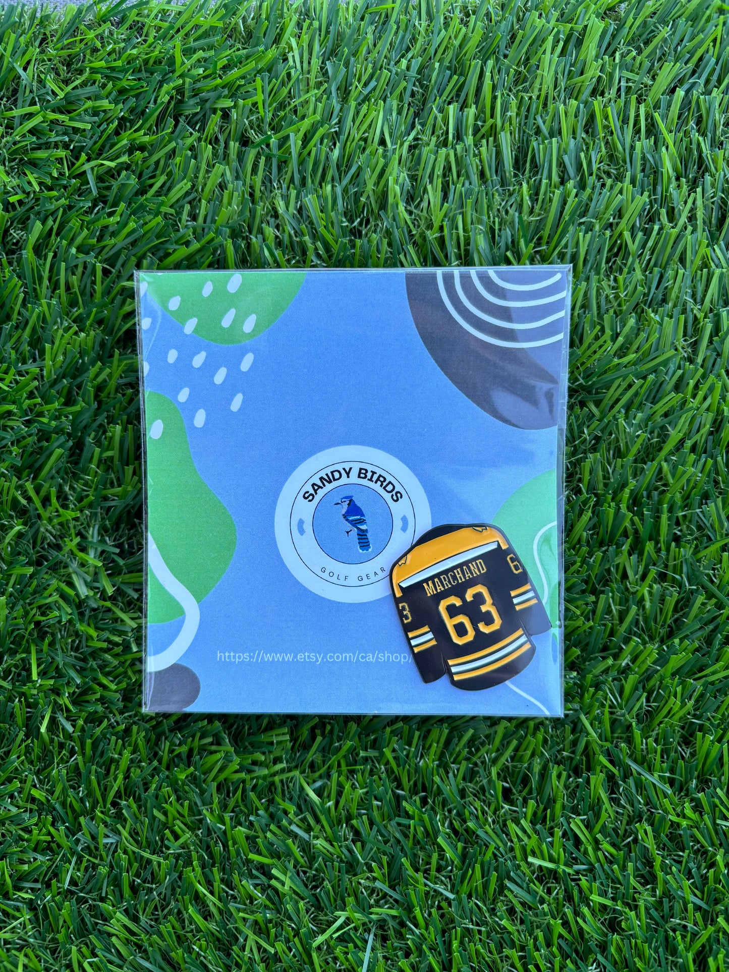 Sandybirds Golf Gear Marchand Ball Marker - Premium quality golf ball marker made of zinc alloy, designed in the shape of a Marchand jersey. A perfect accessory for golf enthusiasts looking to add a touch of style and precision to their game.