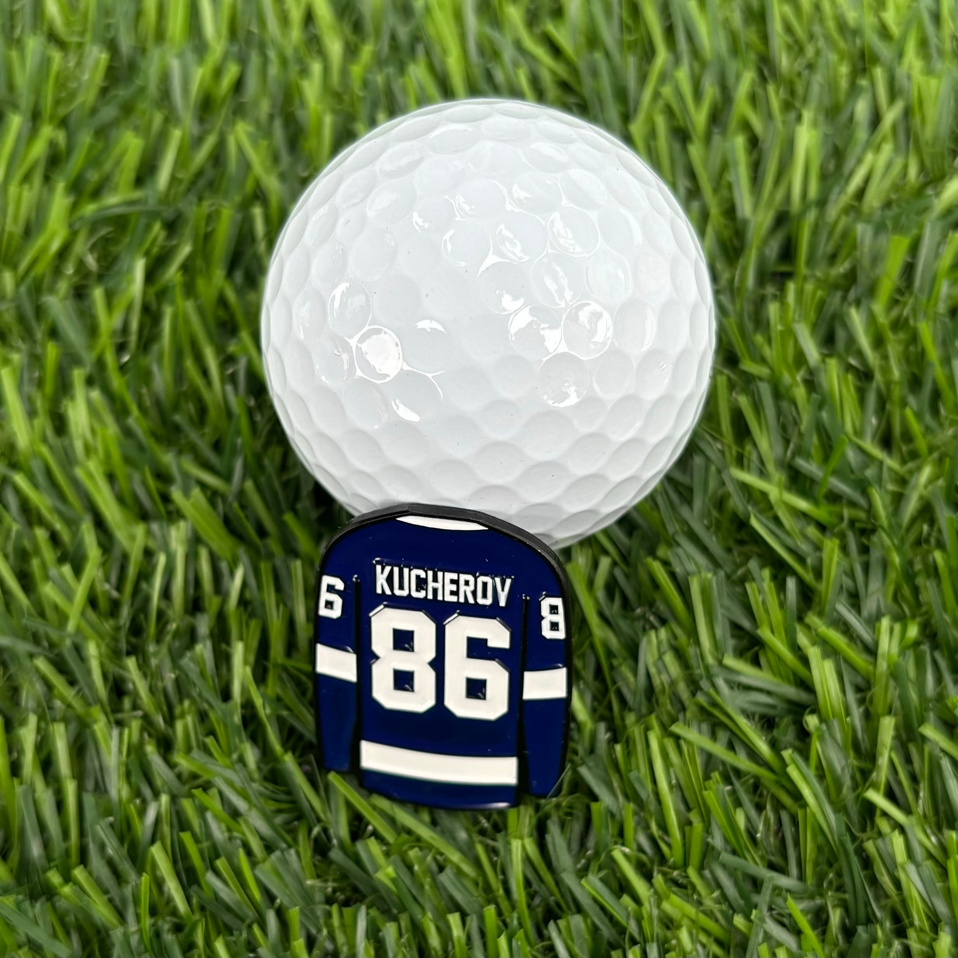 Nikita Kucherov golf ball marker on green grass under a white golf ball