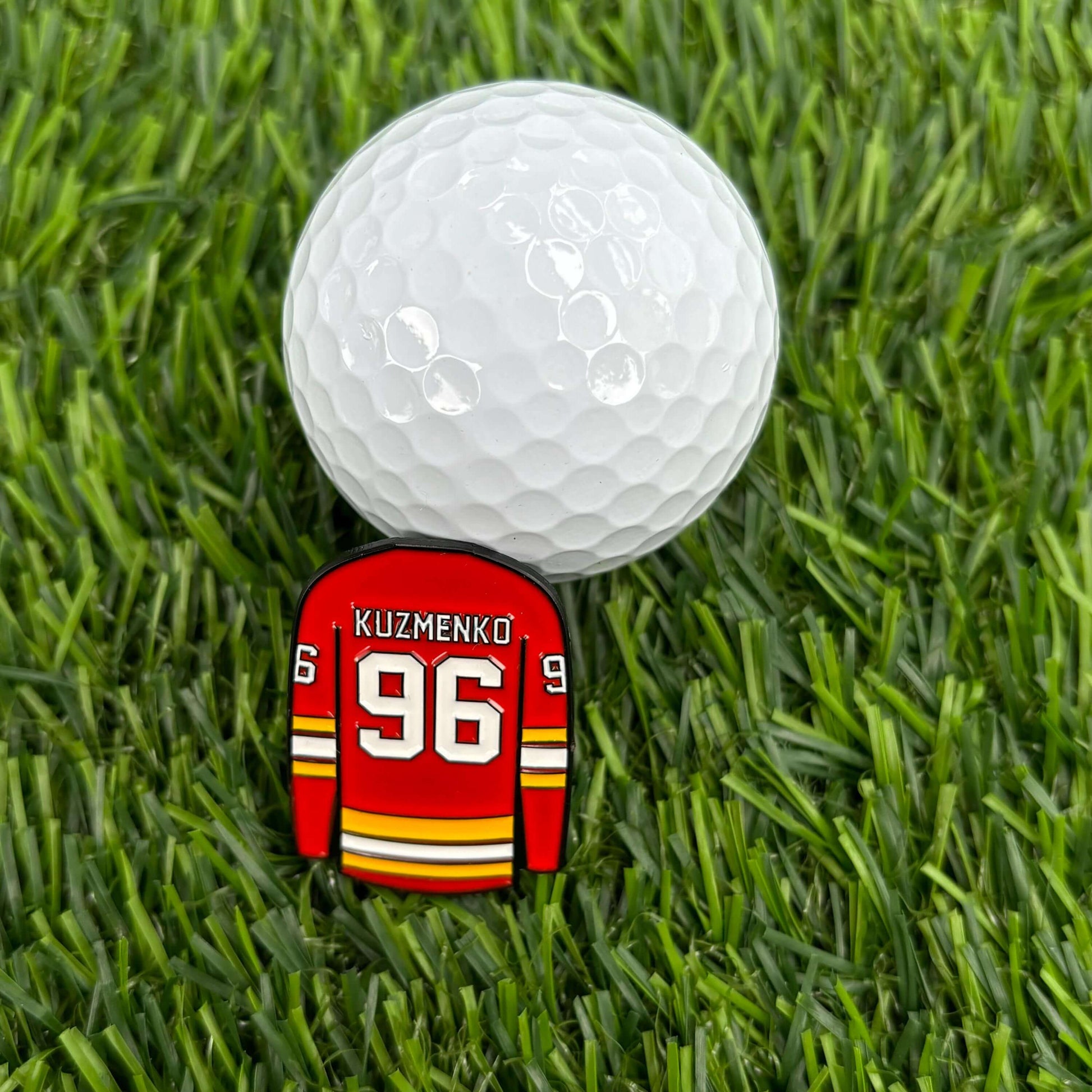 Golf ball on grass with Andrei Kuzmenko custom jersey-shaped golf ball marker