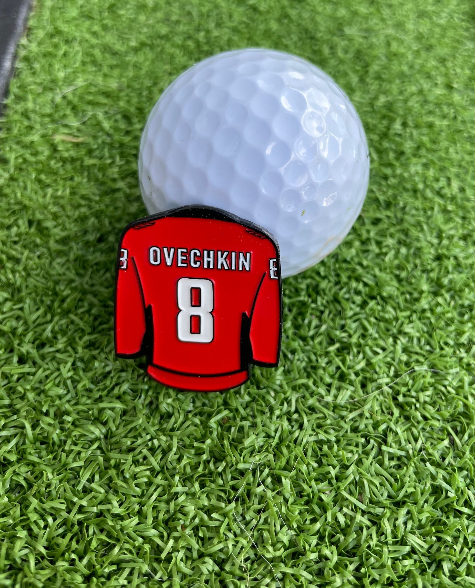 Sandybirds Golf Gear Ovechkin Ball Marker - Premium quality golf ball marker made of zinc alloy, designed in the shape of an Ovechkin jersey. A perfect accessory for golf enthusiasts looking to add a touch of style and precision to their game.